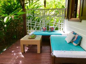 eine Veranda mit einem Sofa und einem Tisch auf dem Balkon in der Unterkunft Titalee Lodge 3 Villas autour d'une piscine in Saint-François