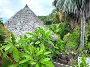 eine strohgedeckte Hütte in einem Garten mit Pflanzen in der Unterkunft MOOREA VILLA KAHAIA in Teavaro