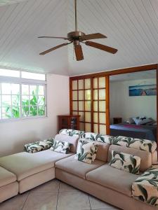ein Wohnzimmer mit einem Sofa und einem Deckenventilator in der Unterkunft MOOREA VILLA KAHAIA in Teavaro