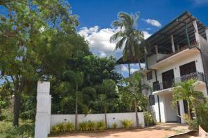 une maison blanche avec une clôture et des arbres dans l'établissement Thinaya lake resort, à Anurâdhapura