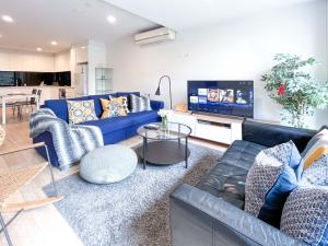 a living room with a blue couch and a tv at Pride Bentleigh Apartment with Private Garden in Melbourne
