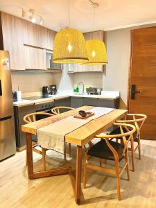 a kitchen with a wooden table and chairs in a kitchen at Moderno depto Edificio Origen cercano al centro in Pucón