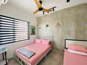 a room with a pink bed and a ceiling fan at Orang Utan Guest House in Sandakan