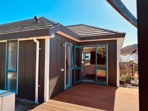 een tiny house met een terras en een slaapkamer bij Observation Guest Suite in Paraparaumu