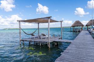 a dock with two chairs and a hammock on the water at LAGOON SPECIAL Suite: Bikes & Kayaks! in Bacalar