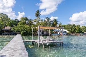 a dock with chairs and a swing in the water at LAGOON SPECIAL Suite: Bikes & Kayaks! in Bacalar