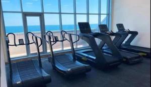 a gym with three treadmills and a view of the ocean at Walk to the Beach, Charming 3-Bedroom Home in Ajman Corniche Residences in Ajman 