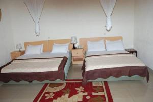 1 dormitorio con 2 camas y alfombra roja en Step Town en Kigali
