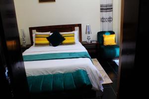 1 dormitorio con 1 cama con almohadas amarillas y verdes en Mamikki Farm and Cottages, en Tororo