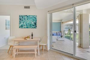 una sala da pranzo con tavolo e sedie e un balcone di The Masthead Iluka Apartment Luxury and Style a Palm Beach