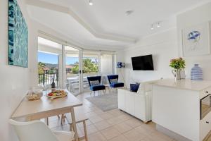 una cucina e un soggiorno con tavolo e sedie di The Masthead Iluka Apartment Luxury and Style a Palm Beach