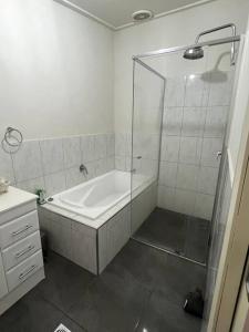a bathroom with a shower and a bath tub at The Cosy House - Central Albury in Albury