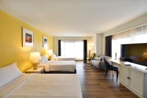 a hotel room with two beds and a flat screen tv at Grand China Bangkok in Bangkok