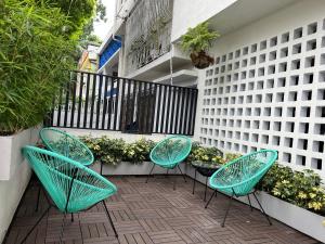 un patio con 3 sillas verdes y un balcón en HOTEL 9.5 SAN FERNANDO en Cali