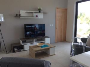 uma sala de estar com uma televisão de ecrã plano e uma mesa em 65/66 South Beach Apartment em Blue Bay