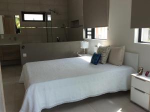 um quarto com uma grande cama branca num quarto em 65/66 South Beach Apartment em Blue Bay