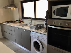 uma cozinha com uma máquina de lavar roupa e um micro-ondas em 65/66 South Beach Apartment em Blue Bay