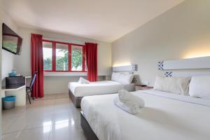 a hotel room with two beds with red curtains at Swing & Pillows - PJ SS2 in Petaling Jaya