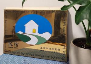 una caja de una señal de alojamiento junto a una planta en 定春行旅 Haru Guesthouse, en Tainan