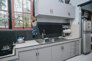 a kitchen with white cabinets and a sink and a refrigerator at Agus Hidden Homestay - Banjar Sweet Village-Ijen in Banyuwangi