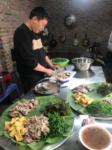 a man preparing food on a table with plates of food at Little Ta Van Homestay in Sa Pa