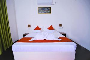 a bedroom with a large bed with red and white sheets at Rekawa Lagoon Resort in Tangalle