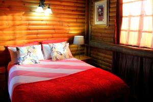 een slaapkamer met een bed in een blokhut bij Ndlovu Log Home Dinokeng in Klipdrift