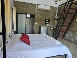 a bedroom with a bed with red pillows and a staircase at ไร่ปาริชาติ in Ban Khanong Phra Tai