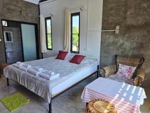 a bedroom with a large bed and a chair at Parichat house ไร่ปาริชาติ in Ban Khanong Phra Tai