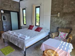 a bedroom with a large bed and a chair at ไร่ปาริชาติ in Ban Khanong Phra Tai