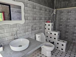 a bathroom with a toilet and a sink and a brick wall at Parichat house ไร่ปาริชาติ in Ban Khanong Phra Tai