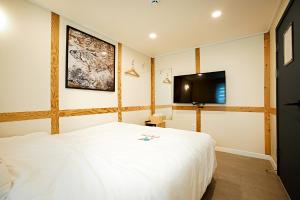 a bedroom with a white bed and a flat screen tv at Geonmaek Stay in Mokpo