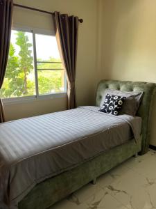 a bed in a bedroom with a window at New Home Yบ้านเดี่ยวสร้างใหม่ ใกล้ทะเล ใจกลางเมืองระยอง in Ban Chak Phai