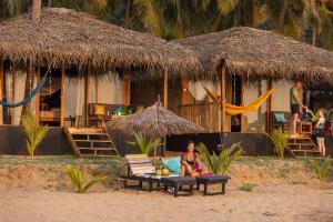 a woman sitting on a bench on the beach at Bamboo Yoga Retreat in Canacona