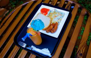 a tray with a plate of food and a drink at Greenyard Beach Hotel in Entebbe