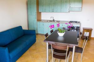a living room with a blue couch and a table with flowers at Case Gialle in San Teodoro