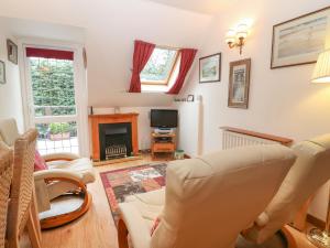 a living room with white chairs and a fireplace at Beech Apartment in Cheltenham