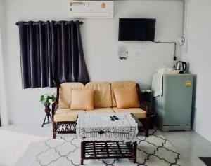 a living room with a couch and a refrigerator at C-Code Resort in Wat Pa