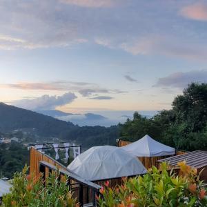 una terraza con sombrillas y vistas a las montañas. en Mon Jaw Doi at Monjam en Chiang Mai