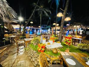 an outdoor restaurant with tables and chairs at night at Lucianas Beach Resort in Marmagao