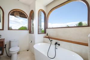 ein Badezimmer mit einer Badewanne und einem WC sowie zwei Fenster in der Unterkunft The Arki Villa in Canggu