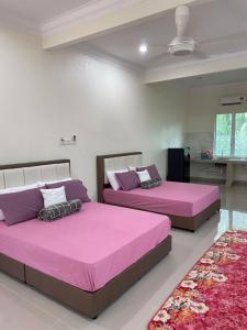 two beds in a room with pink sheets at Akram Homestay in Kota Bharu