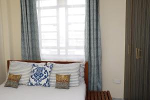 a bed with blue and white pillows and a window at Zanale Stays Furnished Apartment? in Nairobi