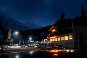 a building with lights on in a parking lot at night at Hotel Cresta in Sedrun