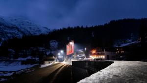 a street at night with a sign in the snow at Hotel Cresta in Sedrun