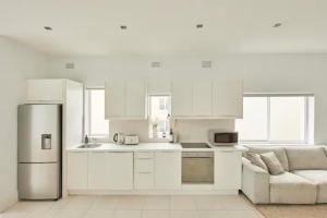 a white kitchen with a refrigerator and a couch at Oceanfront Tamarama Apartment: Best View in Sydney in Sydney
