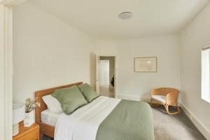 a white bedroom with a bed and a chair at Oceanfront Tamarama Apartment: Best View in Sydney in Sydney
