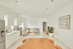 cocina y sala de estar con mesa de madera y sillas en Oceanfront Tamarama Apartment: Best View in Sydney en Sídney