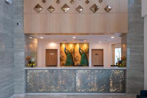 a lobby with three peacock paintings on the wall at ExpoInn Suites and Convention in Greater Noida