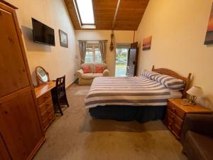 1 dormitorio con 1 cama, vestidor y silla en The Waterings en St. Davids
